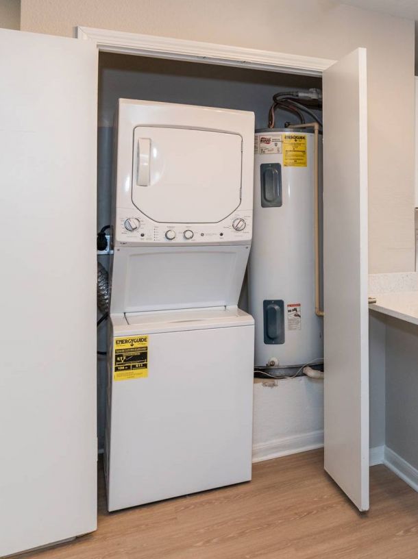 Attain on 5th apartment homes with Stacked washer and dryer unit next to two water heaters inside a closet with open doors.