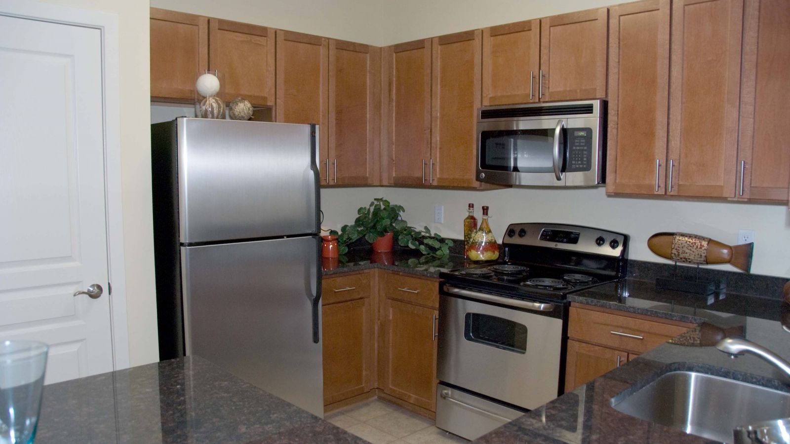 Modern kitchen and living area with white cabinets, stainless steel appliances, and a large island. Cozy seating area with a sofa and rug in the background. Bright and inviting atmosphere.