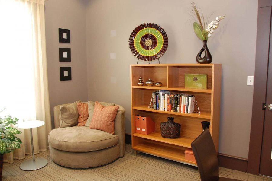 Cozy reading corner with a round beige chair, bookshelf, and modern decor in a well-lit room.