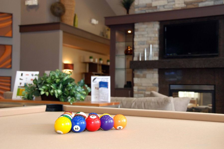A set of billiard balls is racked on a pool table in a cozy living room with a fireplace and TV.