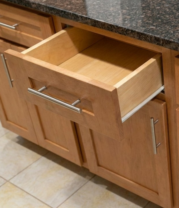A wooden kitchen drawer is open but blocked by a cabinet door beneath it.